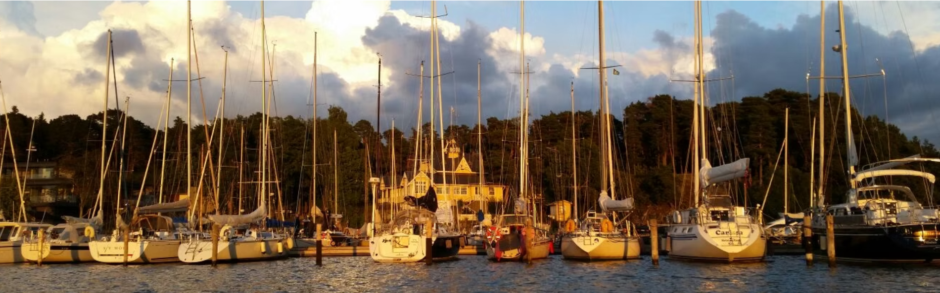 Airisto Segelsällskap clubhouse at golden hour with sailboats moored in the harbour